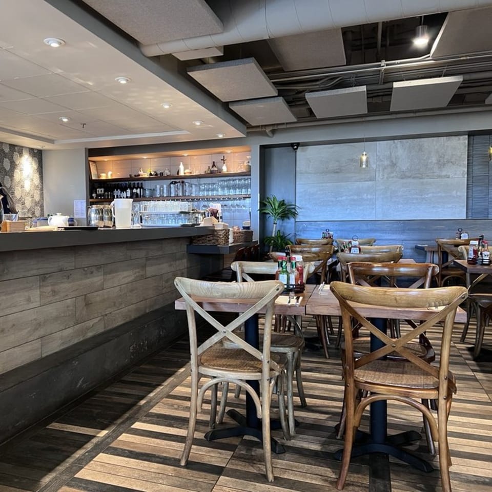 The interior of Surisan restaurant, featuring wooden tables and chairs, a bar area, and modern decor.